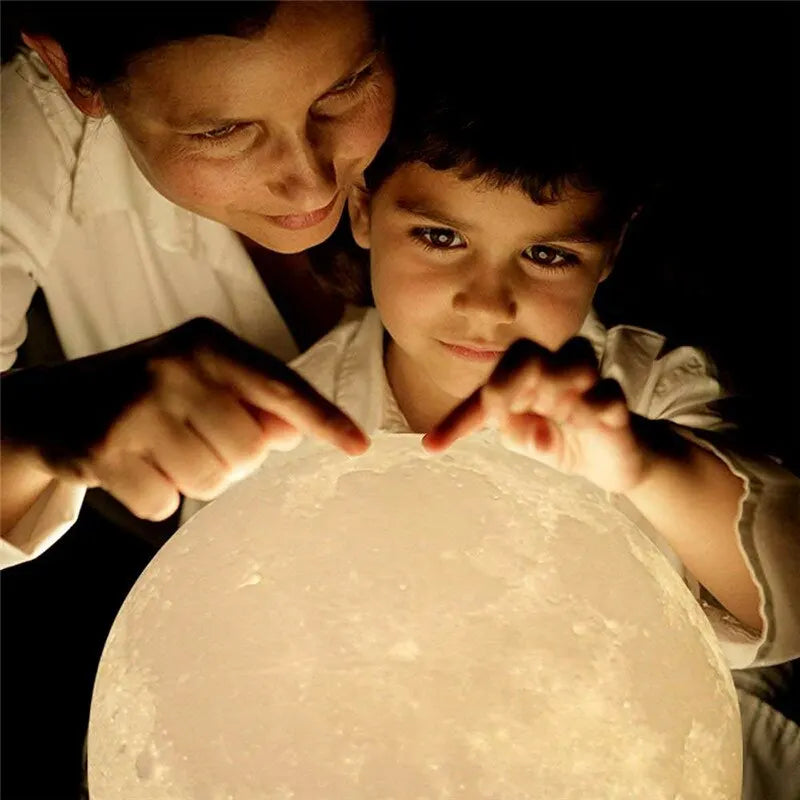 un enfant qui est en train de changer la couleur de la lampe lune féerique en appuyant dessus